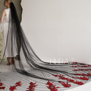 May include: A long, black tulle wedding veil with red floral embroidery along the bottom edge. The veil is shown against a white background. The text "LILIEIA WEDDING VEILS" is visible.