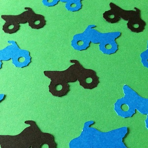 Puede incluir: Una colecci&oacute;n de recortes de papel azul y negro de quads. Los recortes est&aacute;n esparcidos sobre un fondo verde.