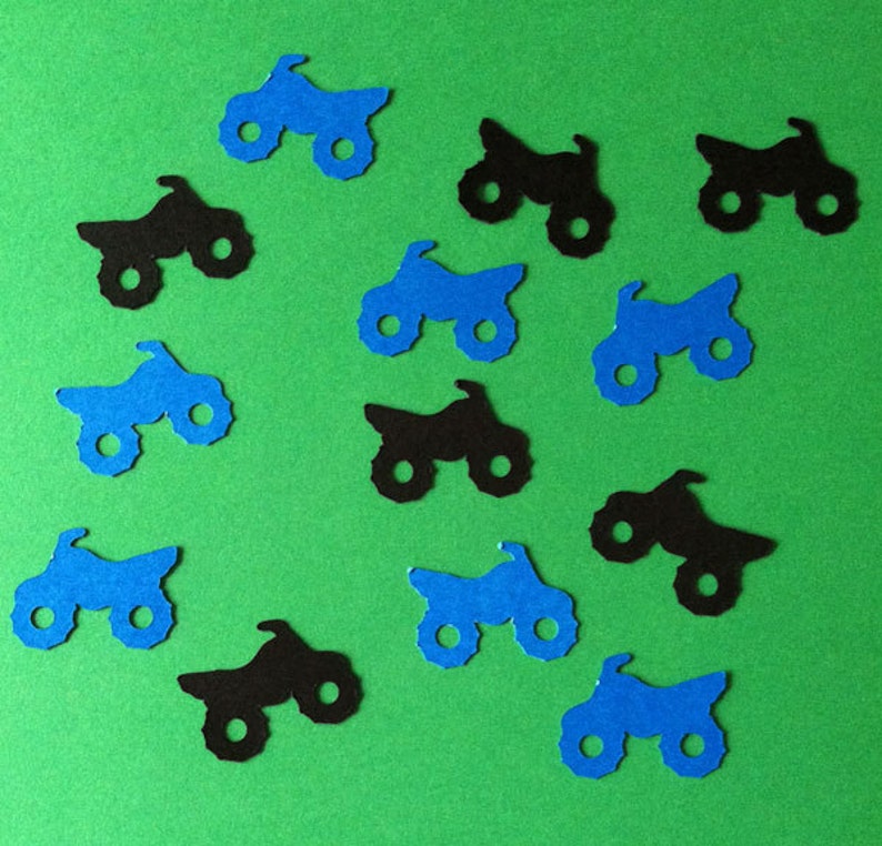 Puede incluir: Una colecci&oacute;n de recortes de papel azul y negro de veh&iacute;culos de cuatro ruedas, que se asemejan a quads o motocicletas todoterreno. Los recortes est&aacute;n esparcidos sobre un fondo verde.