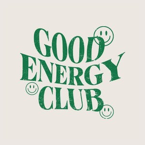 May include: Cream-colored graphic with the words "GOOD ENERGY CLUB" in distressed green lettering. Smiley faces are incorporated into the design. The overall aesthetic is vintage and cheerful.