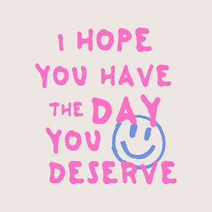 May include: A cream-colored graphic with the text "I HOPE YOU HAVE THE DAY YOU DESERVE" in bright pink, with a blue smiley face. The design has a playful, handwritten style.