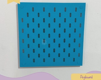 May include: A square, teal pegboard with evenly spaced oval holes. The pegboard has rounded corners and a logo in the top left corner. The text "Pegboard" and "DDDPrint" are in a yellow rectangle in the bottom right corner.