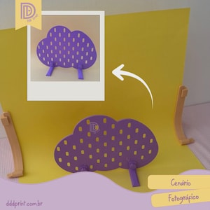 May include: A purple cloud-shaped photography prop with small holes and two purple legs. The prop is on a yellow background with two beige support pieces. The image also includes a smaller image of the prop and the text "Cenário Fotográfico".