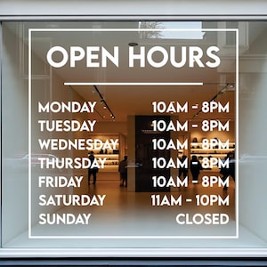 Peut inclure: Une vitrine affiche les horaires d'ouverture en blanc. Le magasin est ouvert du lundi au vendredi de 10h à 20h, le samedi de 11h à 22h et fermé le dimanche. Le texte "OPEN HOURS" est en haut.