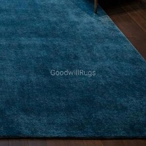 May include: A teal-colored rug with a soft, plush texture. The rug is rectangular and appears to be made of a dense material. The text "GoodwillRugs" is visible on the rug's surface.