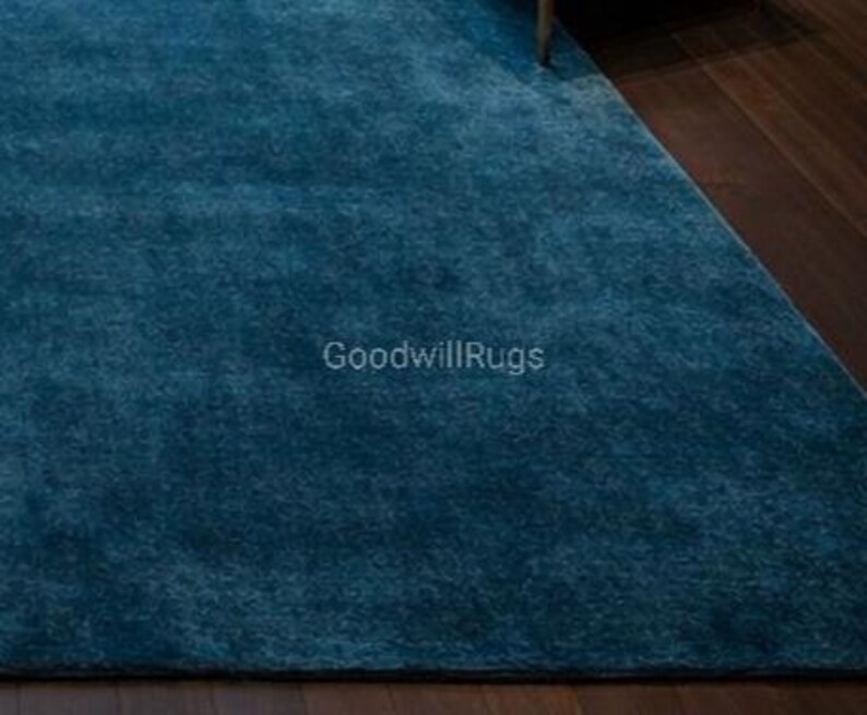 May include: A teal-colored rug with a soft, plush texture. The rug is rectangular and appears to be made of a dense material. The text "GoodwillRugs" is visible on the rug's surface.