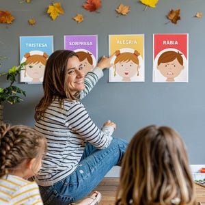 Puede incluir: Una mujer señala cuatro carteles de emociones en una pared gris. Los carteles muestran caras de dibujos animados que representan la tristeza, la sorpresa, la alegría y la ira, con etiquetas de texto. Hojas de otoño decoran la pared sobre los carteles.
