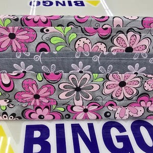 May include: A floral fabric organizer in shades of gray, pink, and green. The fabric features a repeating pattern of stylized flowers and leaves. The organizer has multiple compartments and a handle.