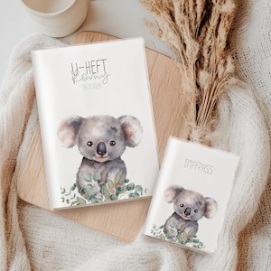 Könnte beinhalten: Zwei weiße Hüllen mit Koala-Bär-Illustrationen. Auf einer Hülle steht "U-HEFT" und "05.11.2024". Auf der anderen Hülle steht "IMPFPASS". Beide Hüllen zeigen einen Koala-Bären im Aquarellstil, umgeben von grünen Blättern.