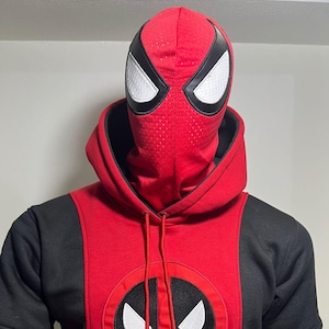 Op de afbeelding: Rode en zwarte hoodie met een Deadpool-logo op de voorkant. De capuchon heeft een mesh masker met witte oogvormen omlijnd in zwart. De tekst "KUSTOMLEATHERDEN" is zichtbaar aan de onderkant.