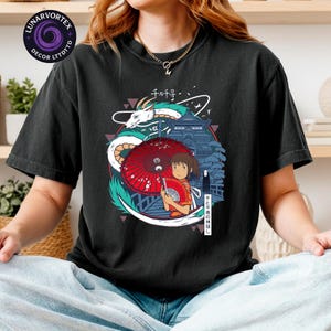 K&ouml;nnte beinhalten: Schwarzes T-Shirt mit einem farbenfrohen Grafikdesign aus dem Anime-Film Spirited Away. Das Design zeigt einen Drachen, ein M&auml;dchen mit rotem Schirm und japanischen Text. Das Shirt hat eine lockere Passform.