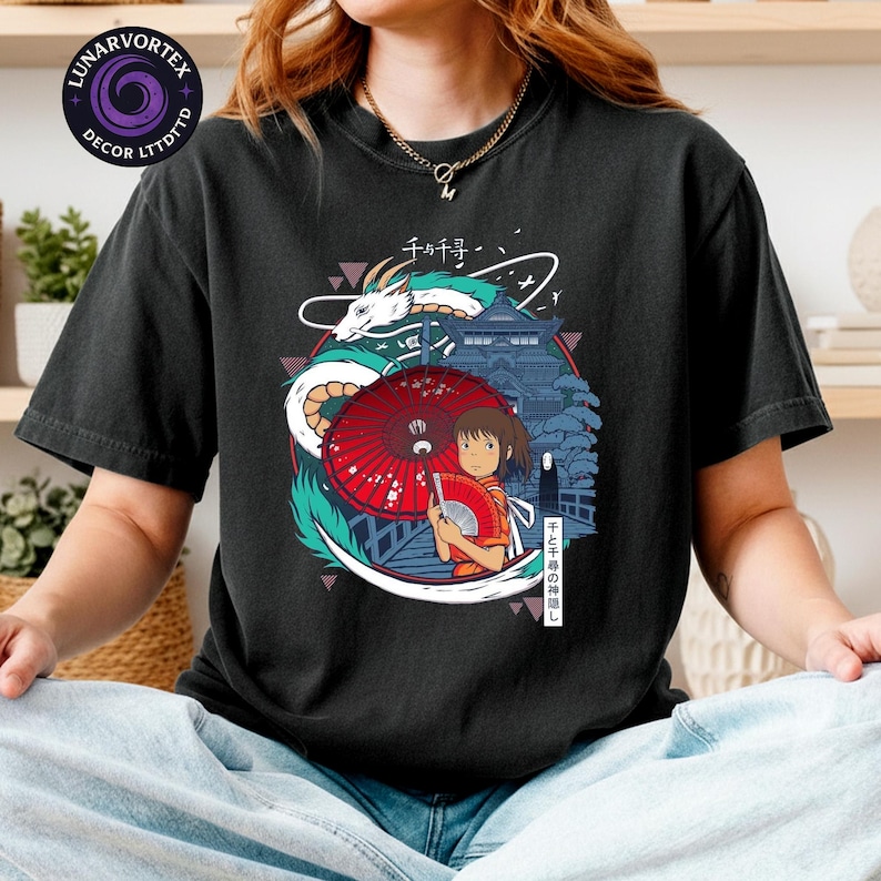 K&ouml;nnte beinhalten: Schwarzes T-Shirt mit einem farbenfrohen Grafikdesign aus dem Anime-Film Spirited Away. Das Design zeigt einen Drachen, ein M&auml;dchen mit rotem Schirm und japanischen Text. Das Shirt hat eine lockere Passform.