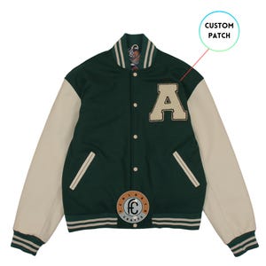 May include: A green and cream varsity jacket with a large letter "A" patch. The jacket features cream-colored sleeves, a striped collar and cuffs, and a circular patch with text. The jacket is buttoned up and has a classic athletic style.