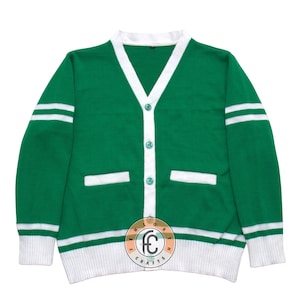 Può includere: Cardigan verde con finiture e dettagli bianchi. Il maglione ha uno scollo a V, chiusura con bottoni e due tasche frontali. Strisce bianche adornano le maniche. L'orlo e i polsini sono bianchi. Un classico stile di maglione.