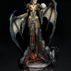 May include: A detailed figurine of a demonic female figure with large wings, horns, and a skull. The figure is dressed in a brown and gold outfit and stands on a stone base with a red demon. The artwork is signed "MINICA ART".