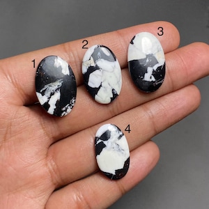 Puede incluir: Cuatro piedras preciosas ovaladas con un patrón en blanco y negro. Las piedras están numeradas del 1 al 4. Las piedras preciosas están pulidas y tienen una superficie lisa. El patrón en blanco y negro varía en cada piedra, creando un aspecto único.
