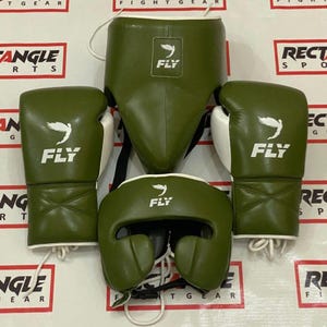 Może przedstawiać: Zestaw oliwkowych ochraniaczy bokserskich, w tym rękawice, kask i ochraniacz na krocze. Każdy element ma białe logo "FLY". Rękawice mają białe akcenty.