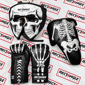 Könnte beinhalten: Ein schwarz-weißes Boxset bestehend aus einem Kopfschutz mit Totenkopf-Grafik, einem Paar 14-Unzen-Schnür-Boxhandschuhen mit Skeletthand-Aufdruck und einem Schienbeinschoner mit einem Design aus Brustkorb und Beckenknochen.