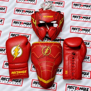 Könnte beinhalten: Ein rotes Boxset bestehend aus einem Kopfschutz, einem Brustschutz und zwei 16-oz-Handschuhen. Jedes Teil zeigt ein gelbes Blitzsymbol und den Text RECTANGLE FIGHT GEAR. Der Kopfschutz hat weiße Schnürsenkel und die Handschuhe verfügen über rote Schnürverschlüsse.