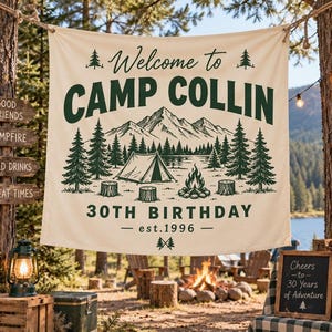 May include: A cream-colored fabric banner featuring dark green text and illustrations. The text reads Welcome to CAMP COLLIN 30TH BIRTHDAY est. 1996. The graphic depicts a mountain range, pine trees, a tent, a campfire, and tree stumps.