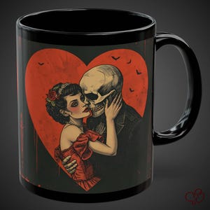 May include: Black ceramic mug featuring a romantic illustration of a skeleton couple embracing within a red heart. The woman wears a red dress and the man is in a suit. Bats fly above the heart. A unique gift for a loved one.