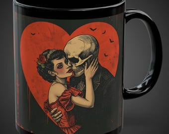 May include: Black ceramic mug featuring a romantic illustration of a skeleton couple embracing within a red heart. The woman wears a red dress and the man is in a suit. Bats fly above the heart. A unique gift for a loved one.