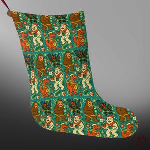 May include: A Christmas stocking featuring a teal background with a repeating pattern of brown bigfoots, white yetis, orange dinosaurs, and black bats. The creatures are decorated with Christmas lights, ornaments, and candy canes. A red ribbon loop is at the top.