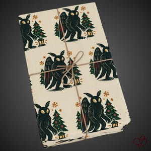 May include: Gift-wrapped package featuring cream-colored paper with a repeating pattern of a dark creature with wings, Christmas trees, lanterns, and snowflakes. The package is tied with twine, creating a rustic and festive look.