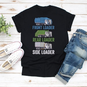Pode incluir: Camiseta preta com ilustrações de três tipos de caminhões de lixo: carregador frontal, carregador traseiro e carregador lateral. O texto abaixo de cada caminhão identifica seu tipo. Tênis brancos e jeans azuis também são visíveis.