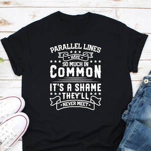 Puede incluir: Camiseta negra con texto blanco: "PARALLEL LINES HAVE SO MUCH IN COMMON IT'S A SHAME THEY'LL NEVER MEET." La camiseta se combina con zapatillas blancas y vaqueros azules. Un diseño humorístico sobre geometría.