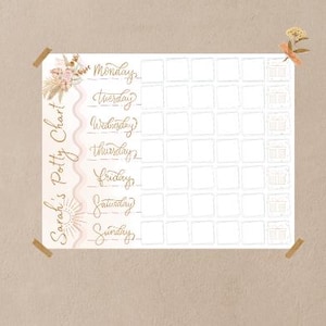 May include: A white potty chart with a floral design and the text "Sarah's Potty Chart" in a script font. The days of the week are listed in a decorative font. The chart is taped to a wall with brown tape.