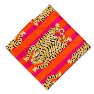 May include: A square, folded silk scarf featuring a tiger design. The scarf has a vibrant orange and pink striped background. The tigers are yellow with black stripes. The scarf is folded in a diamond shape.