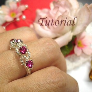 May include: A silver ring with three pink gemstones set in a beaded design. The ring is on a person's finger.