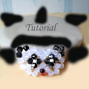 May include: A beaded panda face with black and white beads, a red bead for the nose, and white beads for the eyes.