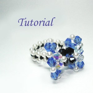 Peut inclure: Une bague en perles avec des cristaux bleus et noirs et des perles blanches. La bague est faite avec un cordon élastique extensible.