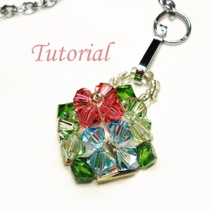 Puede incluir: Una cadena de plata con un cierre de plata unido a un dije de flor de cuentas. El dije está hecho de cuentas de cristal verde, azul y rosa.