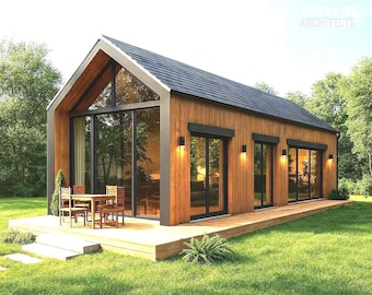 Può includere: Una moderna baita in legno con tetto nero e ampie vetrate. La baita ha un ponte di legno con tavolo e sedie. Il testo "KA ARCHITECTS" è visibile. La baita è circondata da erba verde e alberi.