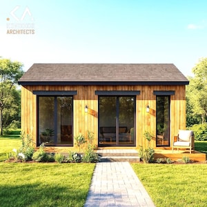 May include: A modern wooden cabin with a dark brown roof and black-framed windows and doors. The cabin has a small deck with a chair and is surrounded by green grass and trees. The text "KOHNOOR ARCHITECTS" is in the upper left corner.