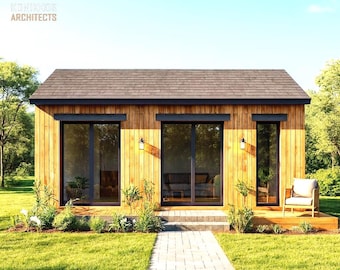 May include: A modern wooden cabin with a dark brown roof and black-framed windows and doors. The cabin has a small deck with a chair and is surrounded by green grass and trees. The text "KOHNOOR ARCHITECTS" is in the upper left corner.