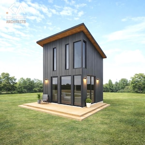 May include: A modern, two-story tiny house with a dark gray exterior, large windows, and a wooden deck. The house has a sloped roof with a light brown overhang. The image is set on a green lawn with trees and a blue sky.