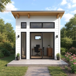 May include: A modern, white home office structure with a light wood roof and trim. The building has black-framed windows and a sliding glass door. The interior features a desk, chair, and cabinet. The structure is set on a wooden deck, surrounded by greenery.