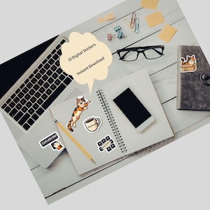 May include: A collection of digital stickers featuring cat-themed designs, including a cat in a box, a cat with a coffee cup, and keyboard keys with the word "MEOW!". The stickers are displayed on a white wooden surface with a laptop, notebook, and smartphone.