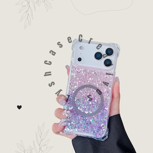 Könnte beinhalten: Transparente Handyhülle mit einem glitzernden, farbverlaufenden Design in Rosa- und Lilatönen. Die Hülle hat ein kreisförmiges Design in der Mitte und der Text "lvshcase" ist am Rand aufgedruckt. Die Handyhülle wird von einer Person gehalten.
