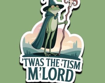 May include: A sticker featuring a cartoon frog dressed as a wizard, wearing a black hat and cape, holding a staff with a skull. The text reads "'TWAS THE 'TISM M'LORD" in white letters.