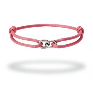 Könnte beinhalten: Ein rosafarbenes Kordelarmband mit zwei ineinandergreifenden, silberfarbenen Metallgliedern in der Mitte. Die Kordel ist strukturiert gewebt und an beiden Seiten mit einem kleinen Knoten versehen, was ein durchgehendes Design mit Akzent ergibt.