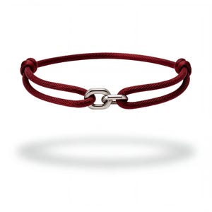 Könnte beinhalten: Ein dunkelrotes Kordelarmband mit einem polierten, silberfarbenen Metallglied als Verbindungsstück in der Mitte. Die Kordel ist durch das Metallglied geführt und mit zwei Knoten auf beiden Seiten befestigt, was eine kreisförmige Form ergibt.
