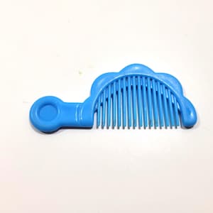 May include: A bright blue plastic comb featuring a semi-circular top edge with a scalloped design and a rounded handle extension on the left side. The comb has a series of evenly spaced, vertical teeth for grooming hair.