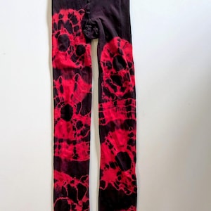 Puede incluir: Mallas negras con un patrón de tie-dye rojo. El patrón está formado por círculos grandes e irregulares.