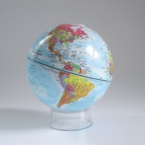May include: A colorful globe with a clear plastic stand. The globe features a detailed map with continents and countries labeled. The text "World Escort Series" is visible. The globe is a great educational tool.