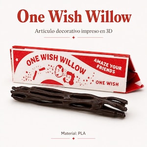 Pode incluir: Um objeto castanho escuro, impresso em 3D, oco e semelhante a um ramo, posicionado em frente a uma caixa triangular vermelha e branca. A caixa apresenta o texto "ONE WISH WILLOW", "AMAZE YOUR FRIENDS" e "ONE WISH", com ilustrações de dois rostos.